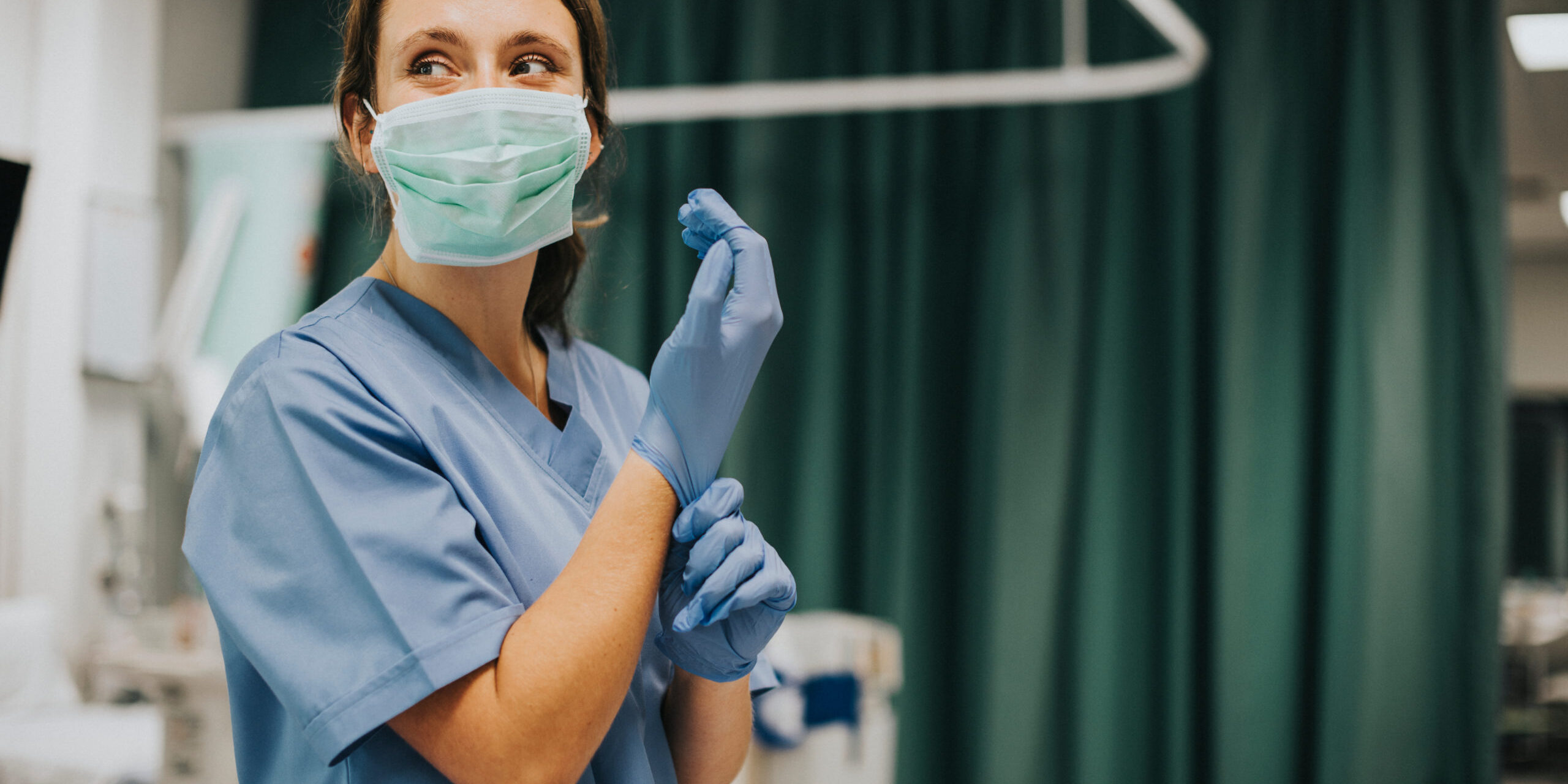 Female,Nurse,With,A,Mask,Putting,On,Gloves